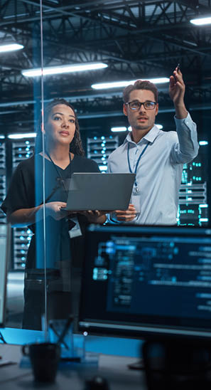 Successful Corporate Top CEO's Talking, Using Laptop Computer Standing in Big City Office at Night. Two Successful Managers Discuss Environmental, Social, Corporate Governance for e-Commerce Project
