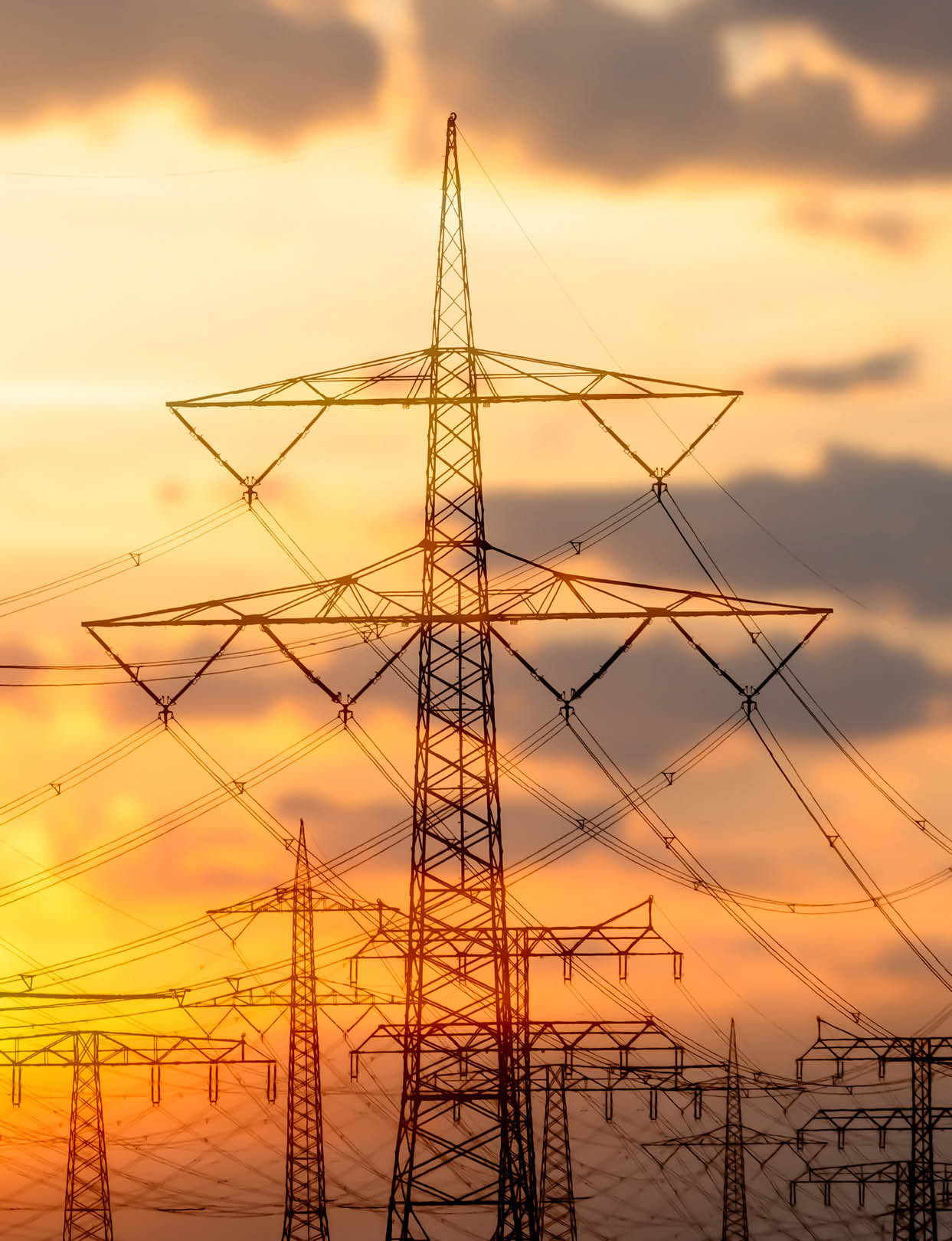high voltage towers with power line grid for transmission of electricity, beautiful industrial landscape with bright sunset light