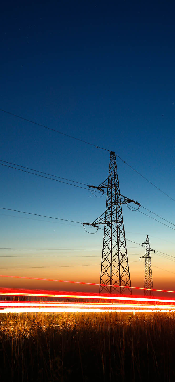 Pylons and electricity powerlines at night with traffic lights in front