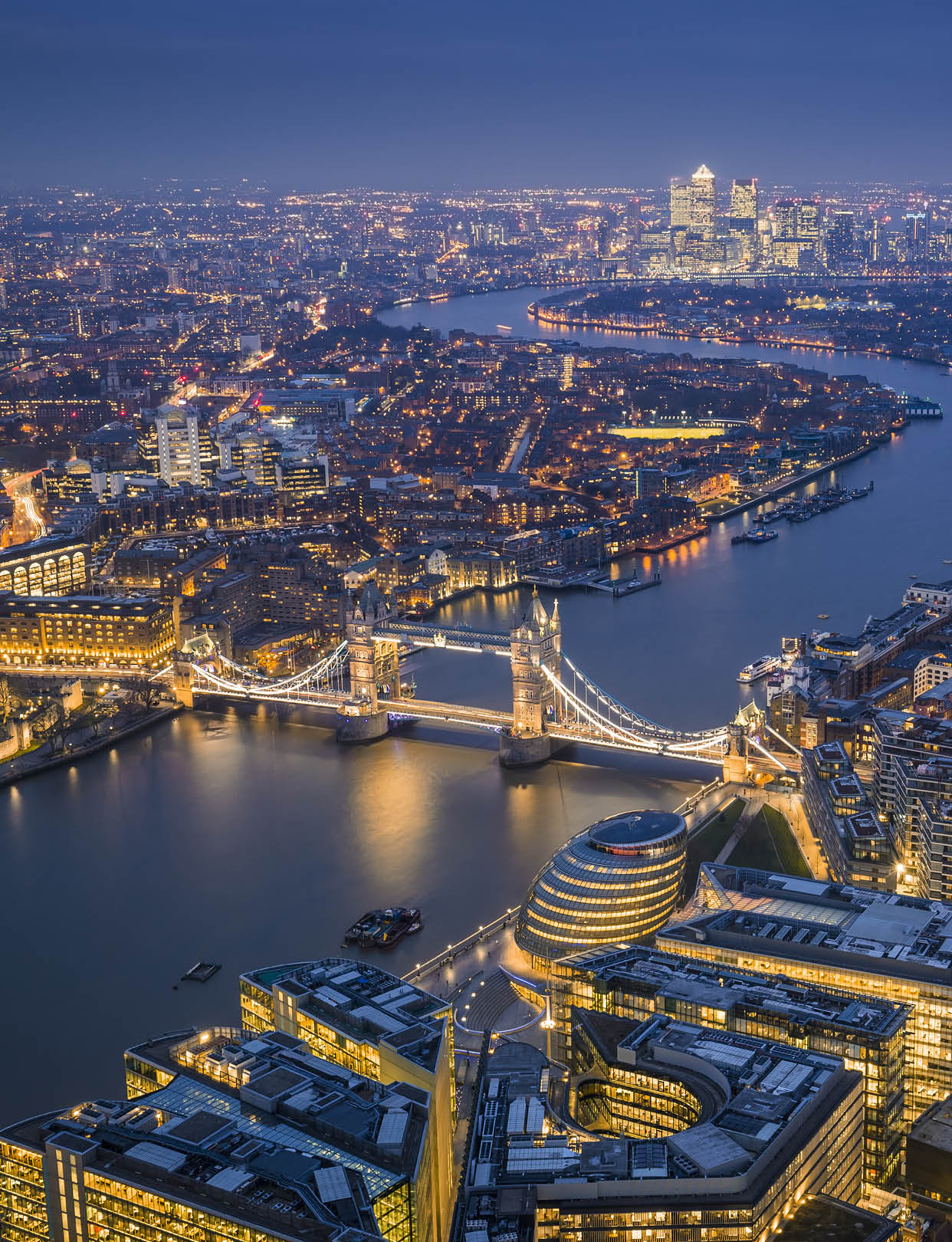 London, England - Aerial Skyline view of London with the iconic Tower Bridge, the Tower of London and skyscrapers of Canary Wharf at blue hour