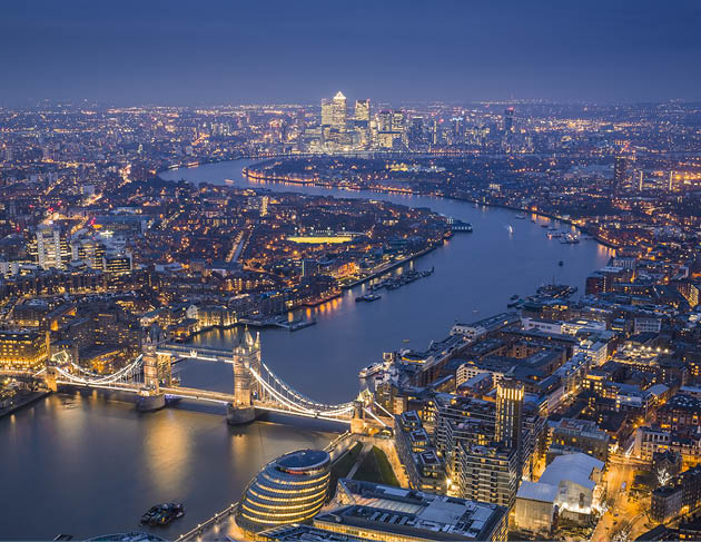 London, England - Aerial Skyline view of London with the iconic Tower Bridge, the Tower of London and skyscrapers of Canary Wharf at blue hour